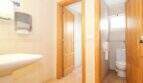 Helles WC mit Waschbecken, Holztüren und Fliesenboden im Stadthaus Portixol, Palma de Mallorca.