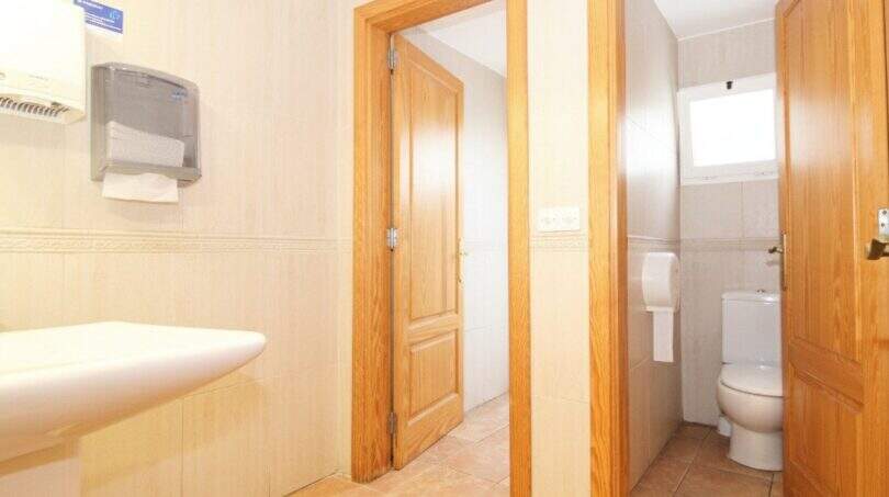 Helles WC mit Waschbecken, Holztüren und Fliesenboden im Stadthaus Portixol, Palma de Mallorca.