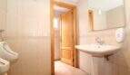 Helles Gäste-WC mit Urinal, Waschbecken, Spiegel und Holztür im Stadthaus Portixol Palma