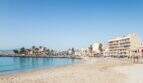 Sandstrand von Portixol mit türkisem Wasser, Palmen und Strandpromenade in Palma de Mallorca