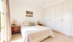 Helles Schlafzimmer der Doppelhaushälfte in Puig de Ros mit Doppelbett, Holznachttischen und weißem Einbauschrank.