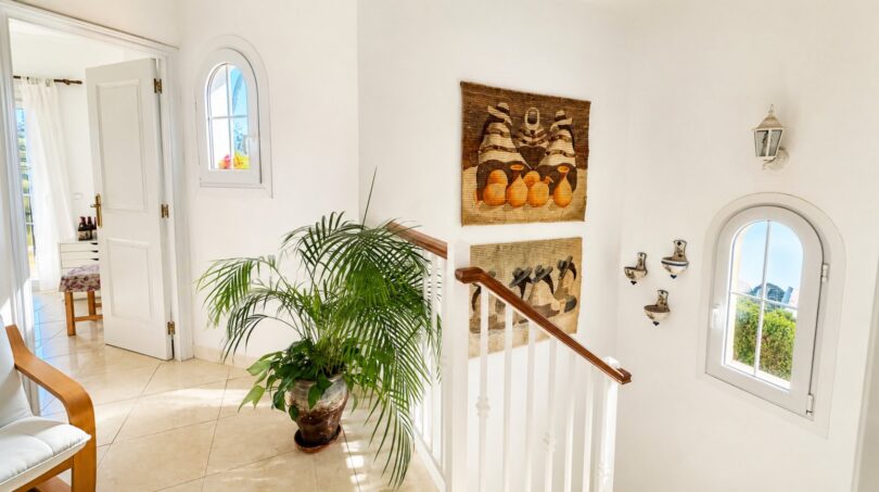 Heller Eingangsbereich mit Treppe, Palme, Wandkunst und Bogenfenstern in exklusiver Doppelhaushälfte in Puig de Ros