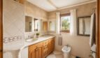 Elegantes Badezimmer der Finca Llucmajor mit Doppelwaschbecken, Holzmöbeln und mediterranen Fliesen