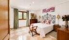Bedroom of the Llucmajor finca with wrought iron bed, parquet floor and green curtains