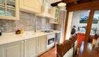 Bright country kitchen with white cabinets, mosaic tile backsplash and wooden beam ceiling of the finca near Llucmajor