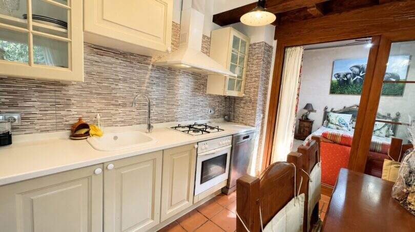 Bright country kitchen with white cabinets, mosaic tile backsplash and wooden beam ceiling of the finca near Llucmajor