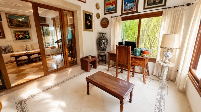 Elegantes Arbeitszimmer der Finca Llucmajor mit Holzmöbeln, Kunstgemälden und Gartenblick