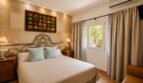 Schlafzimmer der Finca Llucmajor mit Doppelbett, schmiedeeisernem Kopfteil und mediterraner Steinwand