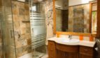 Elegantes Badezimmer der Finca Llucmajor mit Natursteinwänden, Glasdusche und Holzwaschtisch
