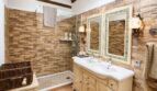 Rustikales Badezimmer der Finca Llucmajor mit Doppelwaschbecken, Glasdusche und Natursteinwänden