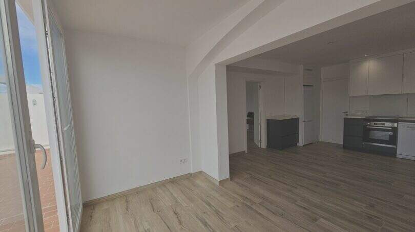 Heller Wohn-Küchenbereich mit Holzböden, weißen Einbauschränken und Zugang zur Terrasse in Erstbezug-Apartment Cala d'Or