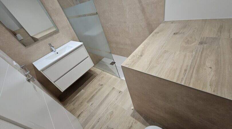 Modernes Badezimmer mit Dusche, schwebender Waschtisch, Holzoptik-Fliesen, Erstbezug Apartment Cala d'Or