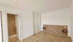 Helles Schlafzimmer mit Holzboden, Einbauschrank, Holz-Kopfteil und angrenzendem Bad in Apartment Cala d'Or