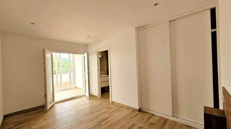 Helles Schlafzimmer mit Holzboden, Einbauschrank, Terrassenzugang und angrenzendem Bad in Erstbezug-Apartment Cala d'Or.