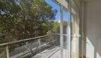 Moderner Balkon mit Glasgeländer und Blick auf grüne Pinien, Wohnung in Palma mit Tiefgarage.
