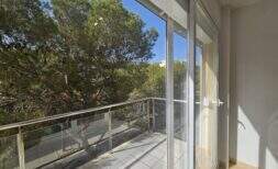 Moderner Balkon mit Glasgeländer und Blick auf grüne Pinien, Wohnung in Palma mit Tiefgarage.