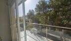 Moderner Balkon mit Glasgeländer und Blick auf grüne Bäume und Nachbargebäude in Palma