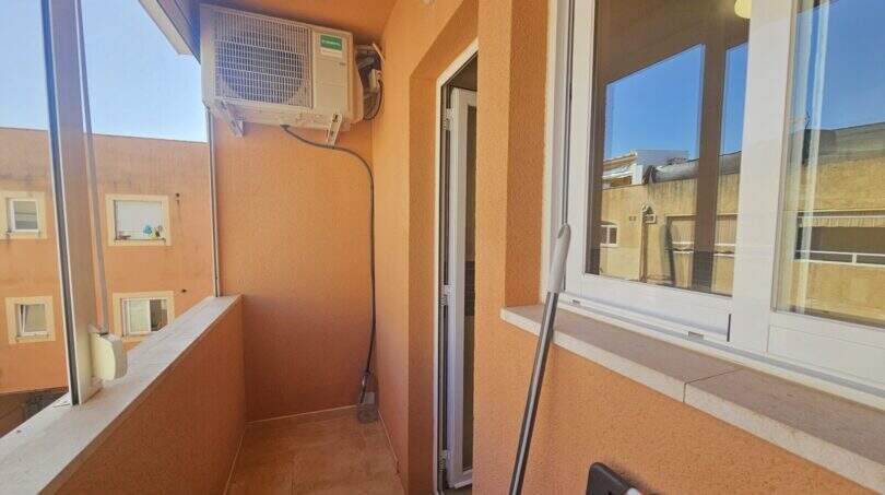 Verglaster Balkon der Wohnung in Palma mit Klimaanlage, Fliesenbelag und Blick auf Nachbargebäude