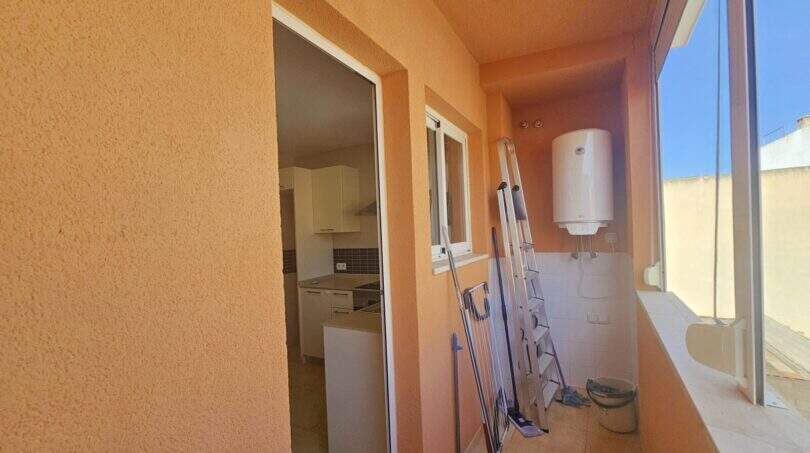Überdachte Terrasse mit Boiler, Reinigungsutensilien und Blick in die Küche der Wohnung in Porto Cristo.