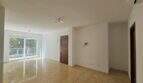 Helles, leeres Wohnzimmer mit Fliesenboden, Balkontür und Holzeingangstür in Wohnung in Palma