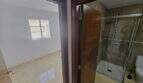 Durchgang zwischen hellem Zimmer und modernem Duschbad mit Glasdusche und WC in Wohnung in Porto Cristo