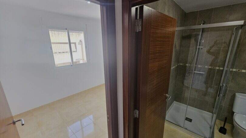 Durchgang zwischen hellem Zimmer und modernem Duschbad mit Glasdusche und WC in Wohnung in Porto Cristo