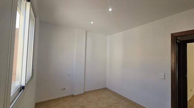 Leeres, helles Schlafzimmer mit Fliesenboden, Einbauspot und Fenster in Wohnung mit Dachterrasse in Porto Cristo