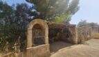 Rustikale Steinmauer mit Rundbogentor und überdachtem Bereich auf renovierungsbedürftiger Finca in Porto Cristo