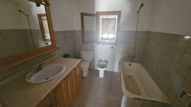 Renovierungsbedürftiges Badezimmer der Finca in Porto Cristo mit Badewanne, Bidet, WC und Holzwaschtisch.