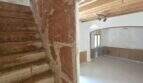 Rustikale Steintreppe und leerer Wohnraum mit Holzbalkendecke und Rundbogen in renovierungsbedürftiger Finca Porto Cristo