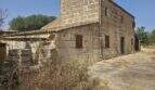Außenansicht renovierungsbedürftige Finca Porto Cristo: historisches Sandsteingebäude mit Nebengebäuden und weitläufigem Grundstück.