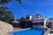 Exterior view: Mediterranean holiday home in Cala Romántica with blue pool, sun terrace and lush greenery under a bright blue sky.