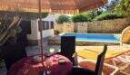 Sonnige Poolterrasse mit Strohdach, Loungemöbeln und Natursteinmauer der mediterranen Villa in Cala Romántica