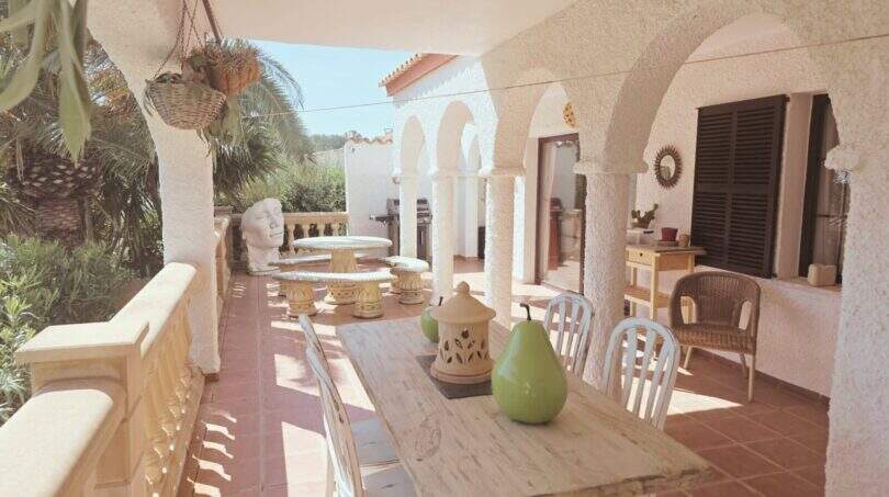 Überdachte Terrasse mit Bogengängen, rustikalem Esstisch und Meerblick des mediterranen Traumhauses in Cala Romántica.