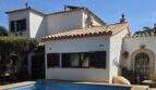 Außenansicht Villa Porto Cristo Novo: weißes Mediterranhaus mit Terrakotta-Ziegeldach, braunen Fensterläden und blauem Pool.