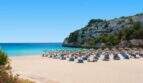 Sandstrand Cala Romántica mit türkisblauem Meer, Liegestühlen und Sonnenschirmen, direkter Strandzugang zum Traumhaus.