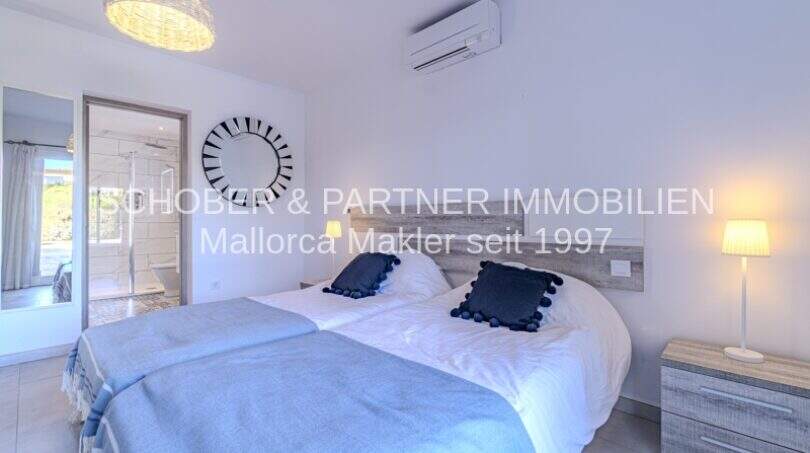 Helles Schlafzimmer der mediterranen Villa in Sa Coma mit Doppelbett, Klimaanlage und En-suite-Bad.