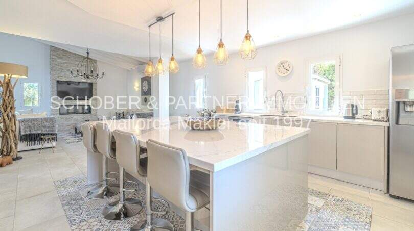 Offene Wohnküche mit weißer Marmor-Kochinsel, modernen Hängeleuchten und elegantem Design in mediterraner Villa Sa Coma