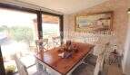 Bright dining room with wooden table, natural stone wall and large glass front with panoramic view in Son Servera