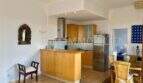 Cocina abierta con frentes de madera y frigorífico de acero inoxidable, zona de comedor adyacente en apartamento del casco antiguo de Palma
