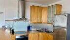 Cocina empotrada moderna con frentes de madera, campana de acero inoxidable, vitrocerámica y frigorífico en apartamento del casco antiguo de Palma