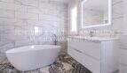 Elegantes Badezimmer mit freistehender Badewanne, Marmorfliesen und modernem Waschtisch in mediterraner Villa Sa Coma