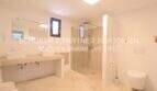 Helles Badezimmer mit Doppelwaschbecken, ebenerdiger Glasdusche und WC im sanierten Landhaus in Portocristo