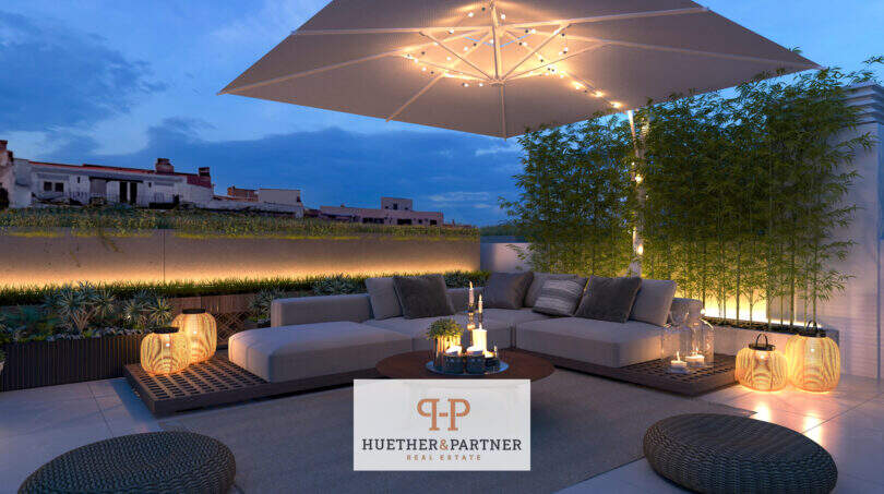 Beleuchtete Dachterrasse des Penthouse Cor 39 in Palma mit Loungemöbeln, Sonnenschirm und Bambus bei Abenddämmerung.