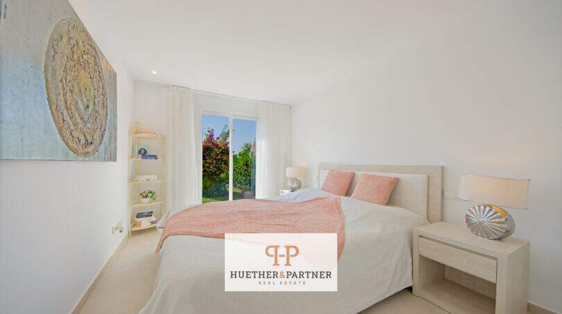 Helles Schlafzimmer im Reiheneckhaus Porto Cristo Novo mit Doppelbett, rosa Akzenten und Gartenblick.