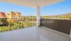 Spacious terrace with tiled flooring, balcony railing and view of Cala Millor and surrounding green spaces.