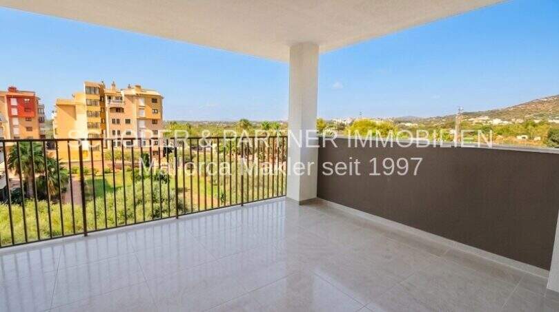 Spacious terrace with tiled flooring, balcony railing and view of Cala Millor and surrounding green spaces.