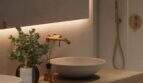 Modernes Badezimmer mit Naturstein-Waschbecken, Holzablage und goldenen Armaturen im renovierten Stadthaus Felanitx