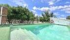 Pool mit türkisem Wasser, Rettungsring und Orangenbäumen der Finca in Campanet unter blauem Himmel.