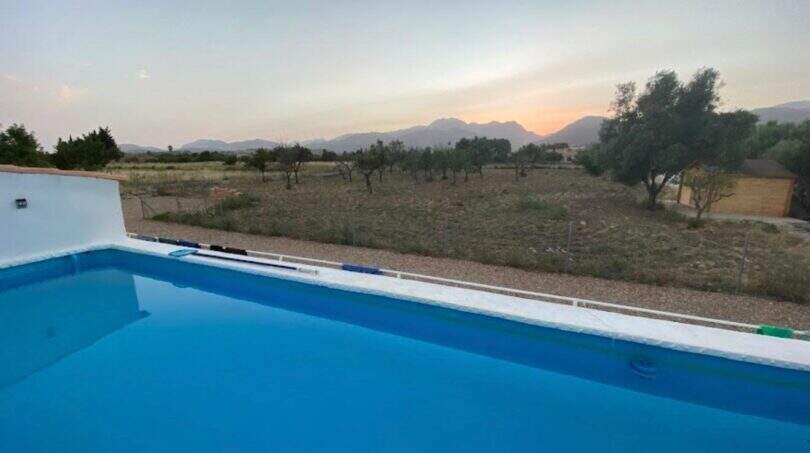 Finca Campanet: Blauer Pool mit Blick auf Olivenhain und Bergpanorama im Abendrot
